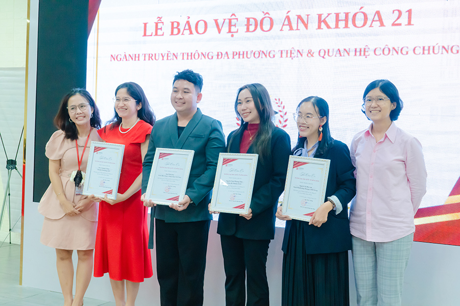 Cô ThS. Nguyễn Ngọc Hạnh My (bìa trái) và Cô ThS. Nguyễn Hương Giang (bìa phải),  cùng Ban giám khảo khách mời chụp ảnh lưu niệm tại Lễ bảo vệ đồ án 88vv1 Khóa 21  ngành 88vv11 Đa phương tiện và Quan hệ Công chúng