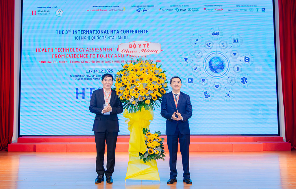 GS.TS Trần Văn Thuấn (trái), Thứ trưởng Bộ Y tế, tặng hoa chúc mừng Ban Tổ chức Hội nghị cho GS.TS.BS Phạm Văn Lình – Hiệu trưởng Trường 88vv 88vvv Hồng Bàng.